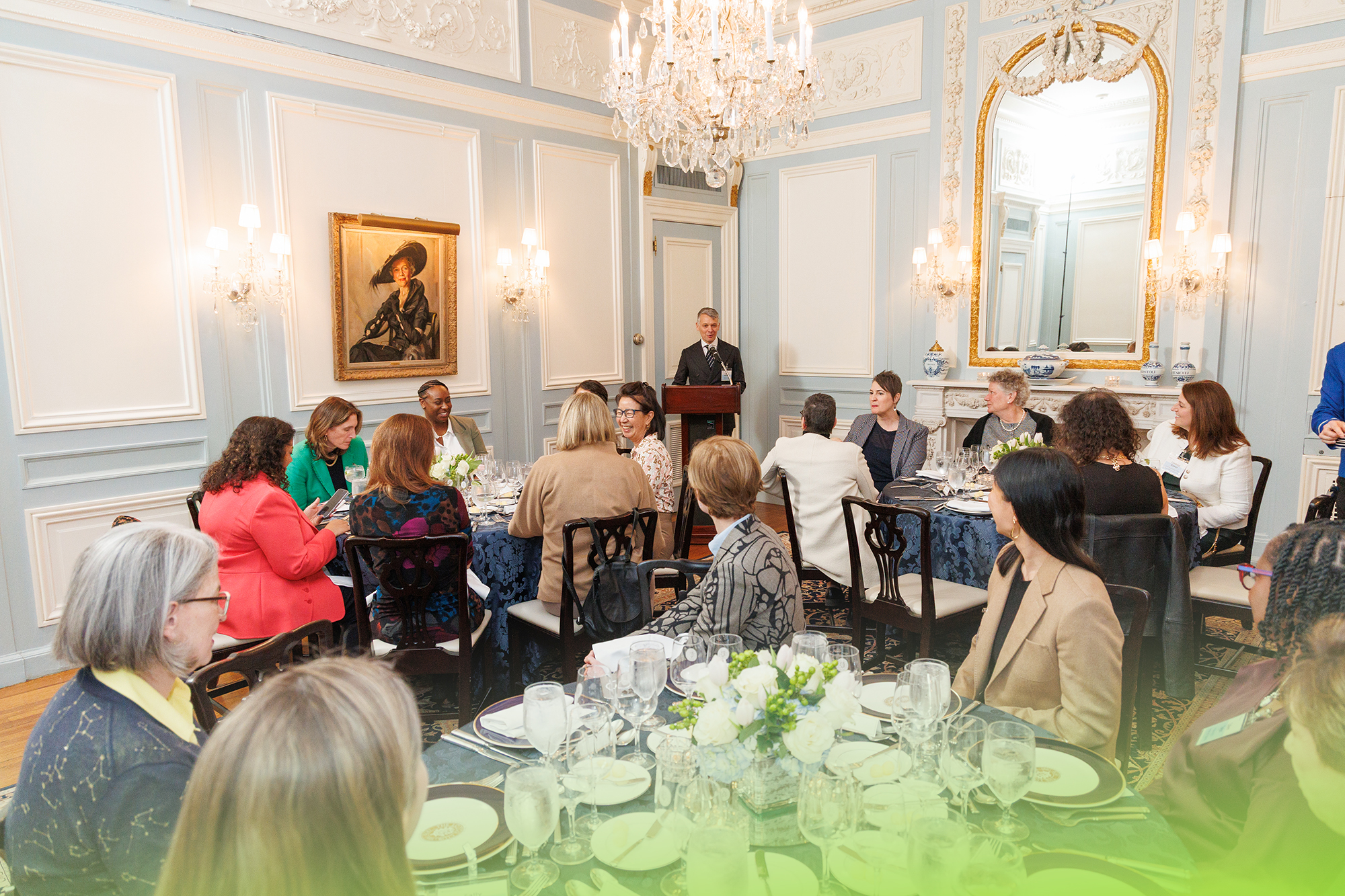 Guests seated at elegantly set tables during an intimate PRISM regional dinner in an ornate dining room.